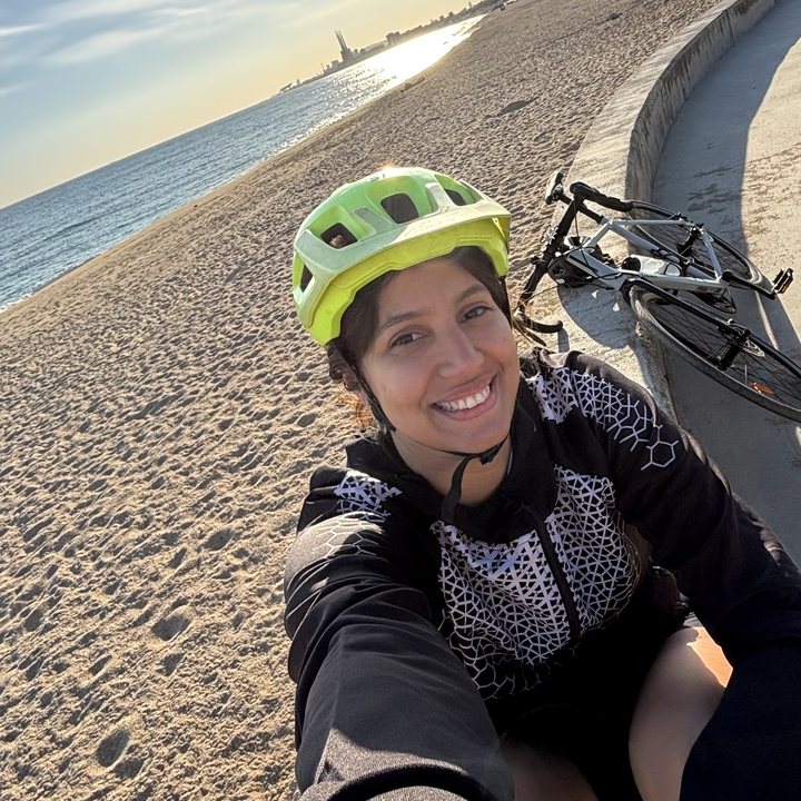 Samantha smiling in a cycling helmet by the sea
